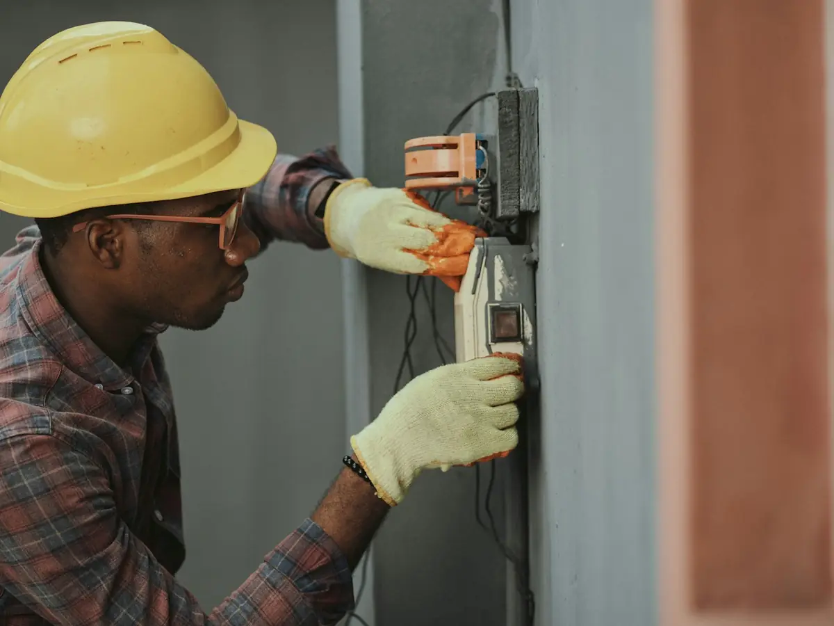 Elektryk w kasku wykonuje pomiary przy instalacji